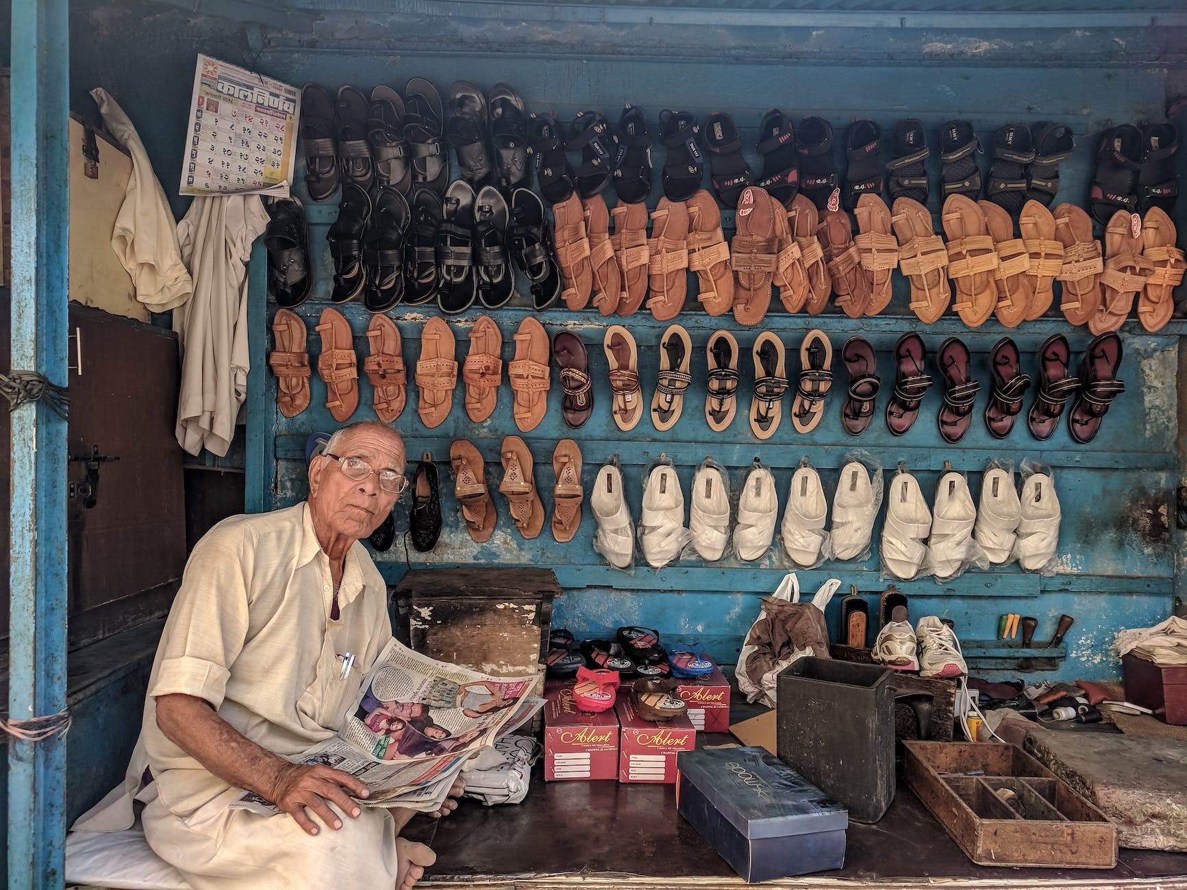 man reading newspaper surrounded by shoes