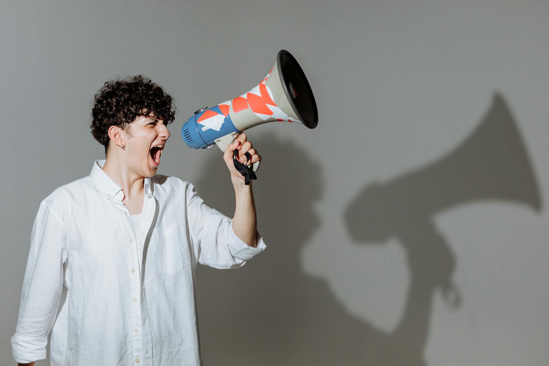 curly haired man shouting through megaphone