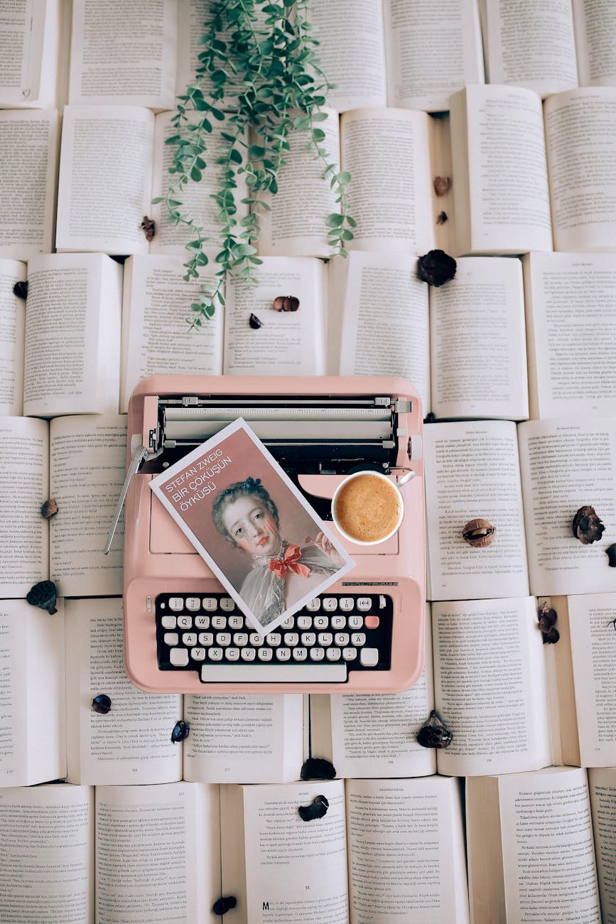 top view of a pink vintage style typewriter leaflet and open books